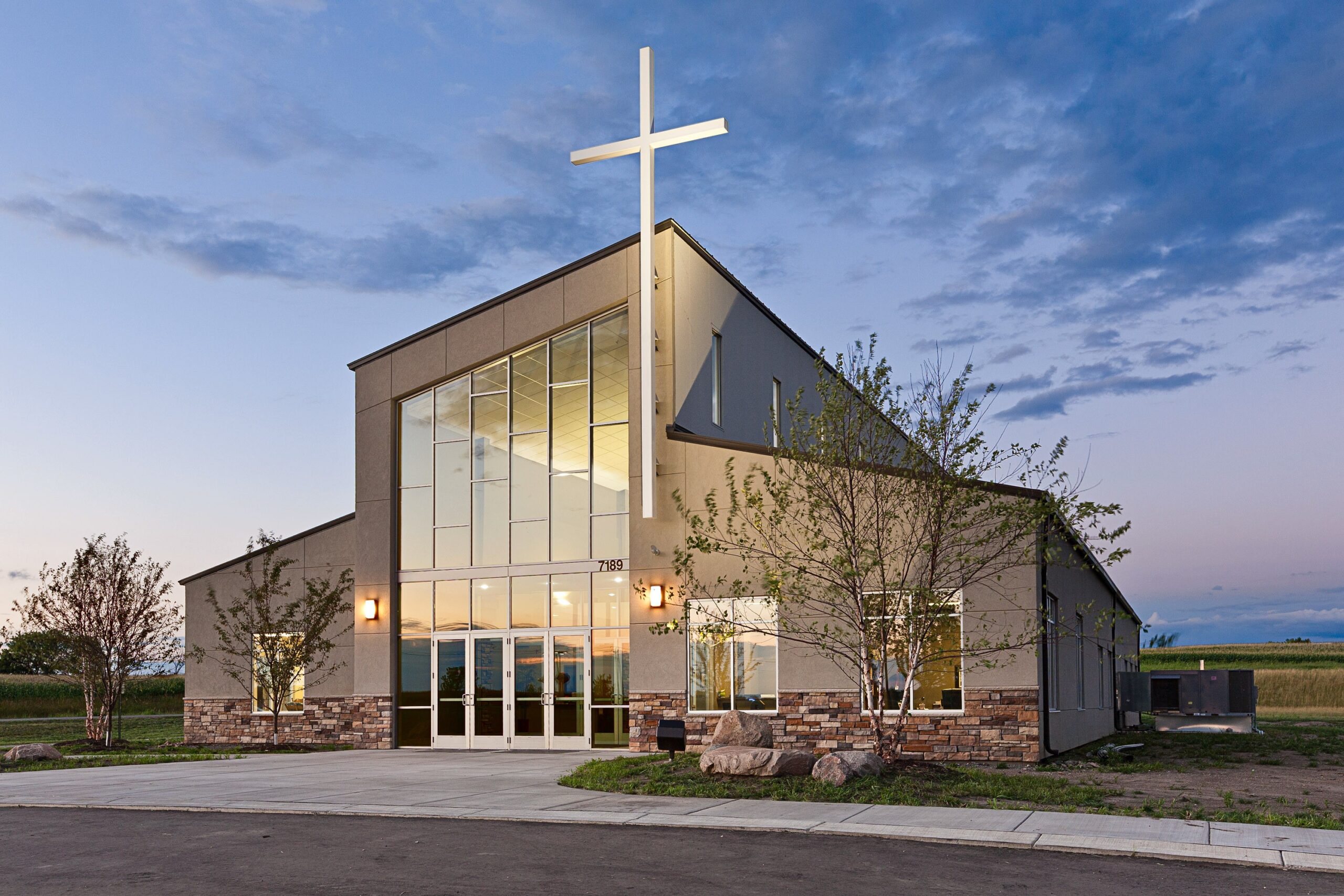 Modern church building with large glass entrance and prominent cross, constructed with Butler metal building systems.